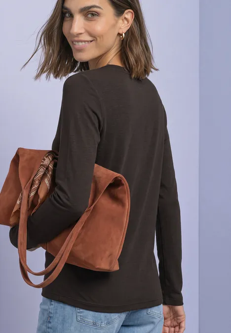 T-shirt basique à col bateau black coffee Eine Frau trägt eine braune Bluse, Jeans und eine große braune Wildledertasche, schaut über die Schulter.