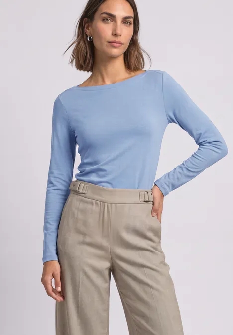 T-shirt basique à col bateau northern blue Frau in hellblauem Langarmshirt und beiger, hochtaillierter Hose mit Gürtelschnalle.