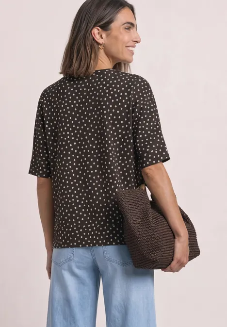 Batwing-shirt met ronde hals en print black coffee Vrouw van achter in bruin shirt met stippen, lichtblauwe jeans, draagt een grote tas over de schouder.