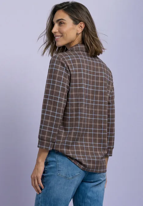 Shirt met 3/4-mouwen van jersey in blouse-stijl silk brown Vrouw met halflang haar draagt geruit overhemd en spijkerbroek, staat opzij en glimlacht.
