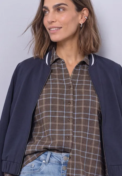 Shirt met 3/4-mouwen van jersey in blouse-stijl silk brown Een lachende vrouw met bruin haar draagt een geruit bruin overhemd en een donkerblauwe bomberjas.