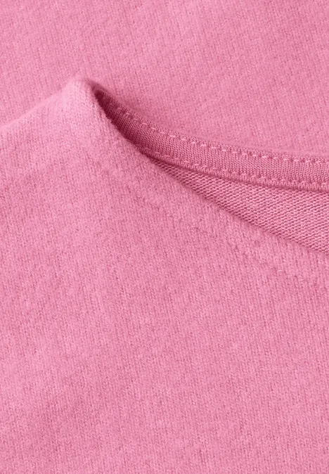 Koszulka z długim rękawem i elastycznym wykończeniem warm blush mel. Zbliżenie dekoltu różowej koszulki z miękkiego materiału.