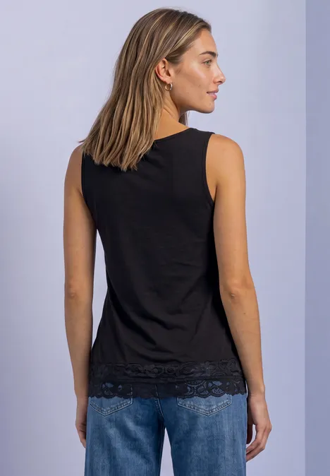 Vue de dos d'une femme portant un top noir sans manches à dentelle et un jean bleu sur fond clair.