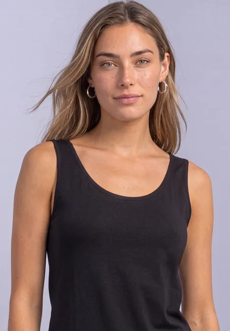 Femme aux cheveux mi-longs portant un débardeur noir devant un fond clair.