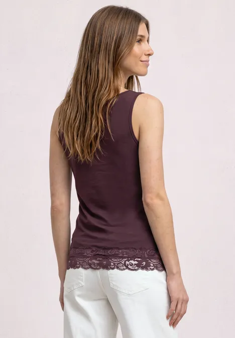 Top mit Rundhals und Spitzenkante rustic rouge Rückansicht einer Frau in ärmellosem, burgunderfarbenem Top mit Spitzenbesatz und weißen Hosen.