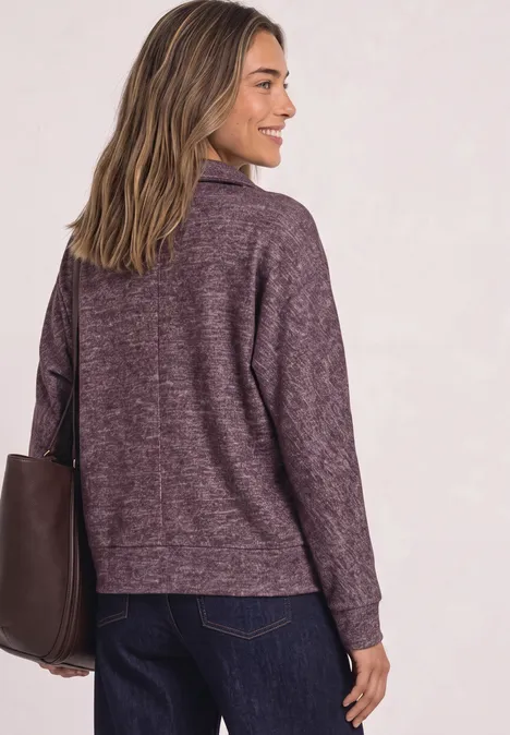Koszulka Polo z długim rękawem w stylu melanżowym rustic rouge mel. Kobieta w fioletowym swetrze i torebce, widziana od tyłu.