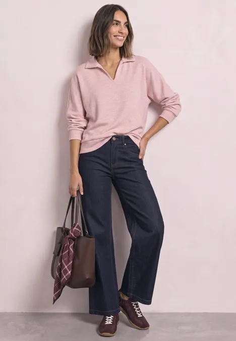 Koszulka Polo z długim rękawem w stylu melanżowym vintage blush mel. Kobieta w różowym swetrze i szerokich jeansach, trzyma brązową skórzaną torbę z kratką.