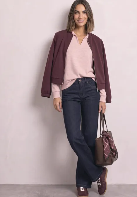 Koszulka Polo z długim rękawem w stylu melanżowym vintage blush mel. Kobieta w casualowo-eleganckiej stylizacji: bordowa kurtka, różowy sweter, ciemne dzwony, brązowa torba i buty.