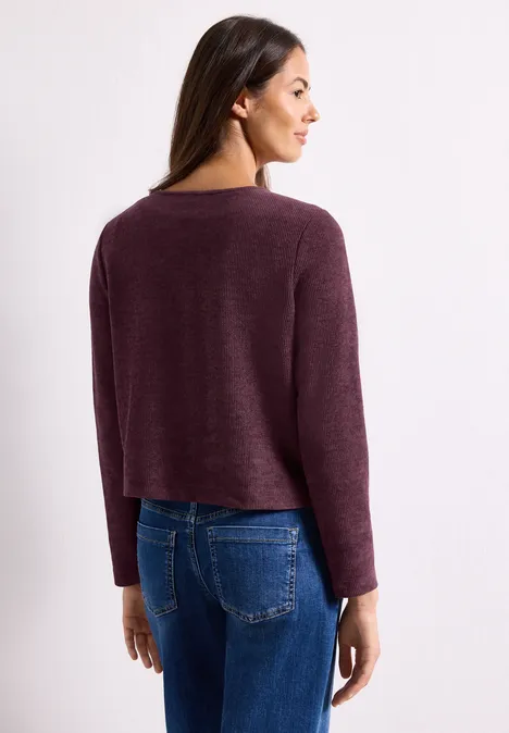 Langarm Jacke mit Rundhals und Knöpfen rustic rouge Frau in weinrotem Pullover und blauen Jeans, Rückansicht, leicht seitlich gedreht.