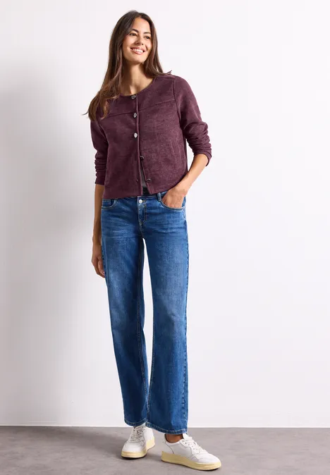 Langarm Jacke mit Rundhals und Knöpfen rustic rouge Eine lächelnde Frau in lila Strickjacke, weiten Jeans und weißen Sneakers vor hellem Hintergrund.