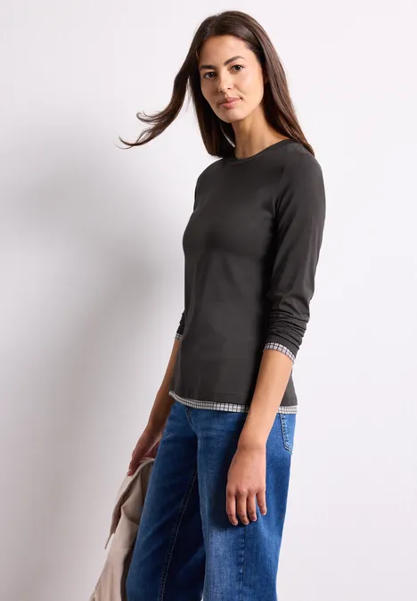 Langarm Shirt mit karierten Meshdetails black coffee Eine Frau in schwarzem Langarmshirt und Jeans hält eine Jacke vor weißem Hintergrund.