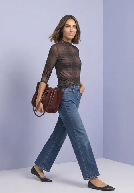 T-shirt à manches longues en mesh, col rond et imprimé sanded amber Frau in karierter Bluse, weiter Jeans und Ballerinas mit brauner Ledertasche vor pastellfarbenem Hintergrund.