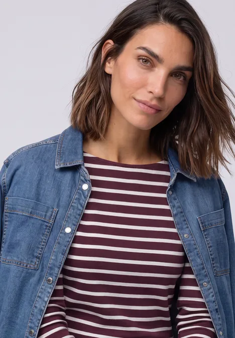 Koszulka z rękawami 3/4, dekoltem w łódkę i w paski rustic rouge Kobieta o brązowych włosach do ramion nosi jeansową koszulę na paskowanym t-shircie.
