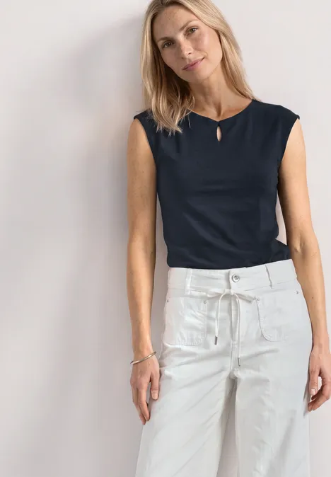 Dropped Shoulder Shirt mit Cut-Out darkest blue Frau trägt schwarzes ärmelloses Top und weiße, hoch taillierte Hose mit Kordelzug und Taschen.