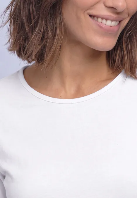 Basic Langarm Shirt in Unifarbe White Nahaufnahme einer lächelnden Frau mit kurzen braunen Haaren, die ein weißes T-Shirt trägt.