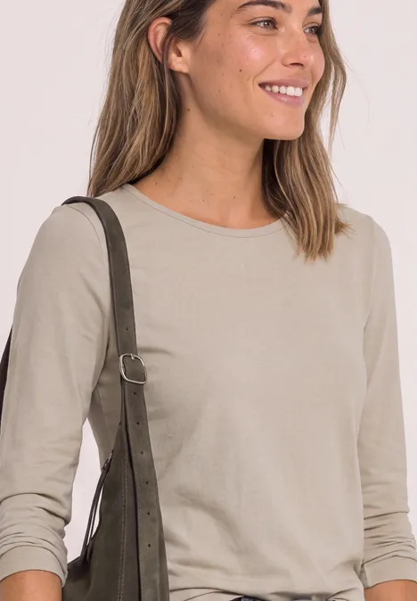 T-shirt basique à manches longues, couleur unie clay sand Lächelnde Frau in beigem Langarmshirt mit grüner Schultertasche.