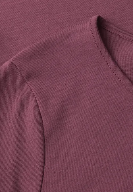 Gros plan sur un t-shirt bordeaux à col rond et couture d'épaule.