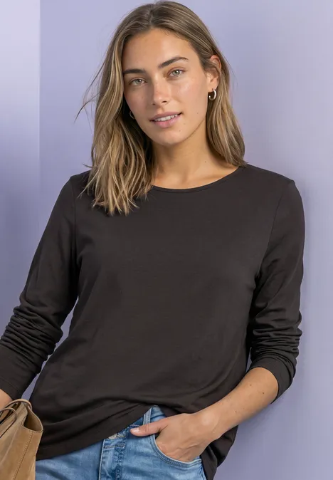 Jednokolorowa koszulka Basic z długim rękawem black coffee Kobieta w brązowej bluzce z długim rękawem i z torebką, swobodnie pozująca na jasnym tle.