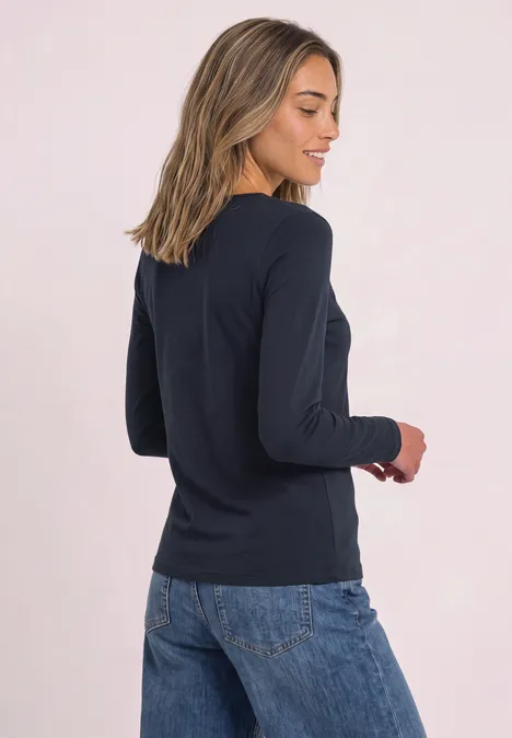 Jednokolorowa koszulka Basic z długim rękawem darkest blue Kobieta w granatowej bluzce z długim rękawem i dżinsach, uśmiechnięta, tułów lekko obrócony na jasnym tle