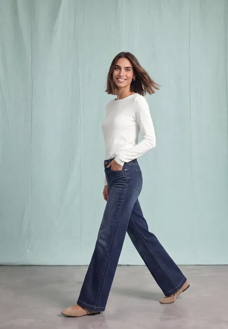 Langarm Shirt mit U-Boot-Ausschnitt off white Lächelnde Frau in weißem Langarmshirt und weiten Jeans, die vor hellem Hintergrund geht.