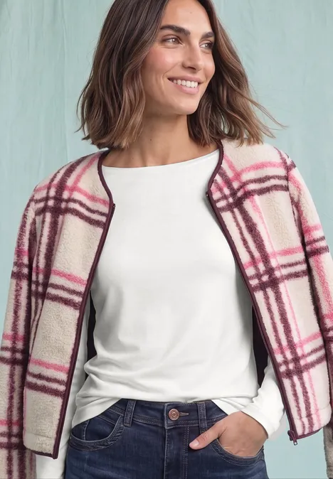 Langarm Shirt mit U-Boot-Ausschnitt off white Eine Frau mit weißem Shirt und rosa kariertem Mantel lächelt vor hellem Hintergrund.