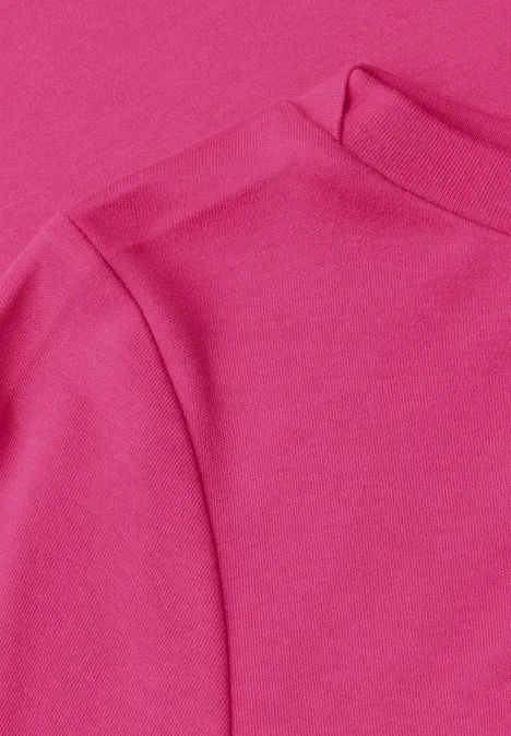 Close-up van een roze kledingstuk met fijne stofstructuur en zichtbare naden.