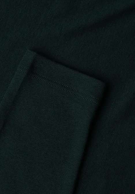 Close-up einer aufgesetzten Tasche aus dunkelgrünem, strukturiertem Stoff.