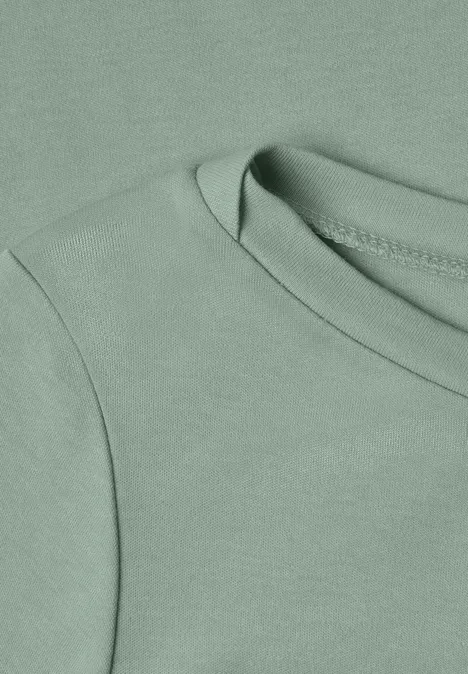 Gros plan d’un t-shirt vert clair avec encolure ronde.
