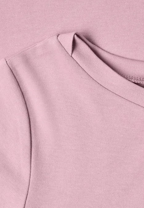 Gros plan d’un t-shirt rose pastel à col rond en tissu doux.