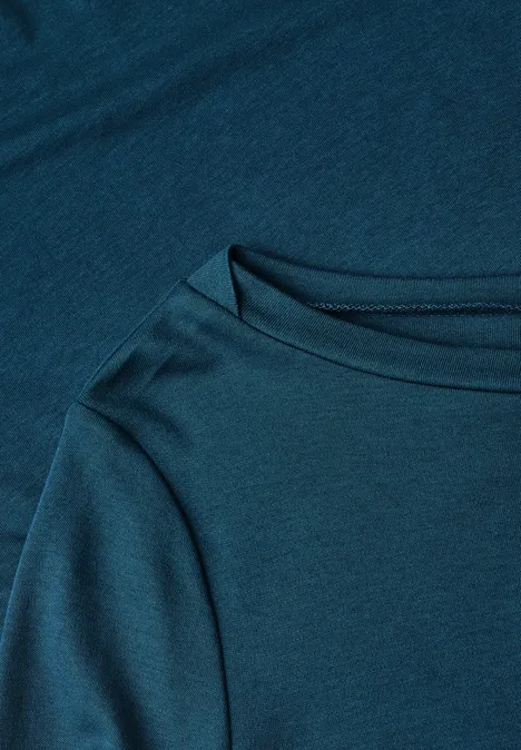 Nahaufnahme eines petrolblauen T-Shirts mit Rundhalsausschnitt und weicher Stoffstruktur.