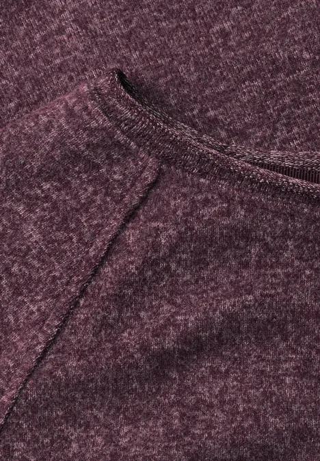 Gros plan sur un tissu tricoté bordeaux, coutures apparentes et texture douce, finement chinée.