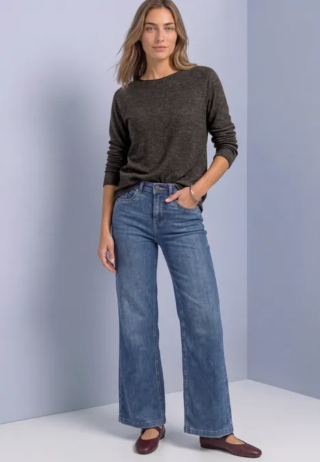 Langarm Shirt mit Rundhals und Rollkante black coffee mel. Frau in grauem Pullover, hoher Taille, weiten Jeans und braunen Schuhen vor schlichtem Hintergrund