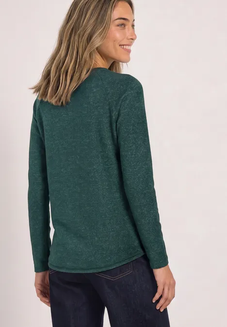 Langarm Shirt mit Rundhals und Rollkante shadow teal Eine Frau trägt ein grünes Langarmshirt und dunkle Jeans, sie steht seitlich und lächelt.