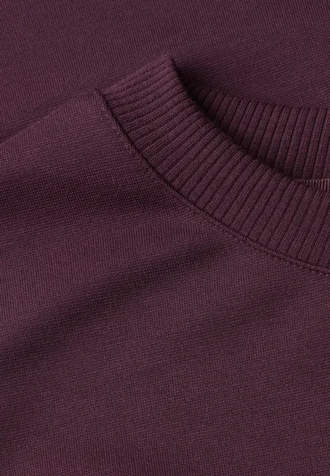 Détail d’un pull bordeaux sombre en maille fine, col rond côtelé
