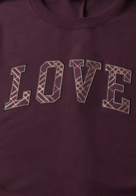 Pull bordeaux avec inscription LOVE en grandes lettres à motif géométrique.