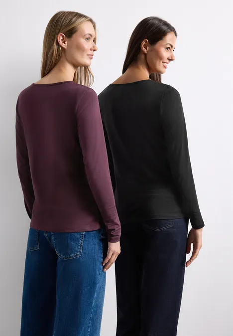 Deux femmes de dos, en tee-shirts à manches longues violet et noir, associées à des jeans.