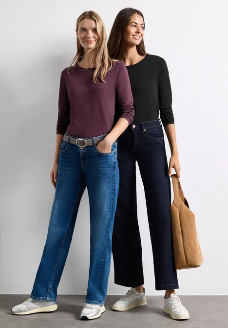 Deux femmes en tenues décontractées, manches longues et pantalons amples, baskets blanches.