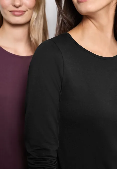 Gros plan sur deux femmes portant des t-shirts à manches longues noirs et bordeaux.