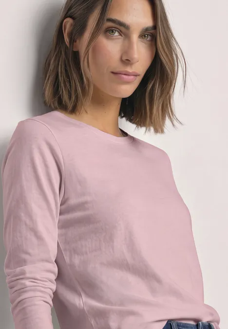 Langarm Shirts mit Rundhals im 2er-Pack off white/quiet rose Frau mit schulterlangem braunem Haar in rosa Langarmshirt vor hellem Hintergrund.