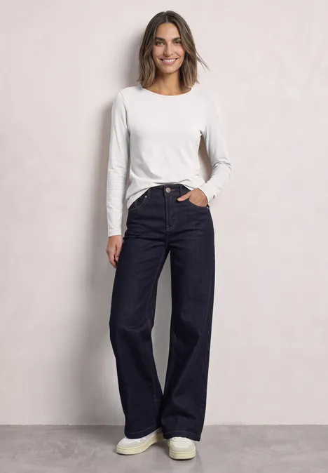 Langarm Shirts mit Rundhals im 2er-Pack off white/quiet rose Eine Frau trägt ein weißes Langarmshirt und weite, dunkle Jeans und lächelt vor hellem Hintergrund.