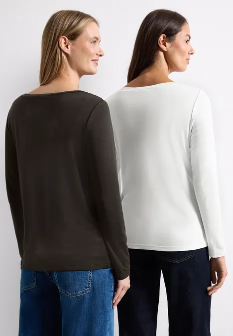 Zwei Frauen von hinten in schlichten Langarmshirts in Weiß und Dunkelgrün vor weißem Hintergrund.