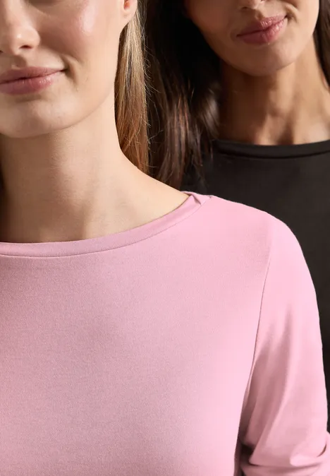 Zwei Frauen tragen schlichte Longsleeves, vorne rosa, hinten schwarz, minimalistisch und elegant fotografiert.