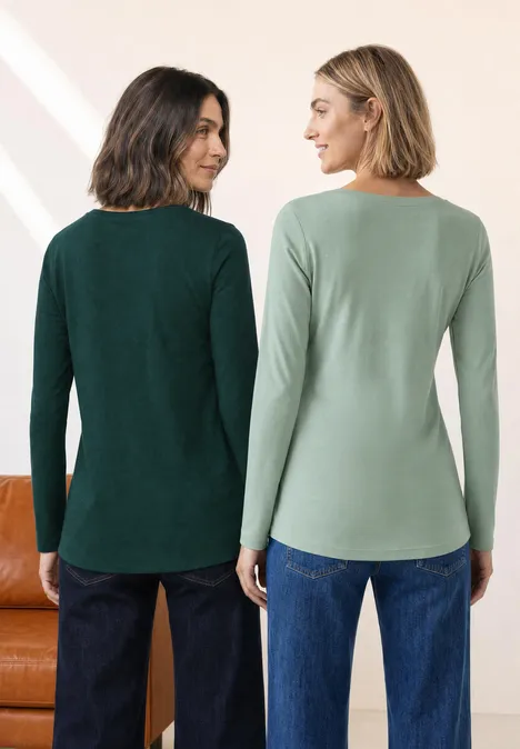Zwei Frauen von hinten in Jeans und langärmligen Oberteilen in unterschiedlichem Grün.
