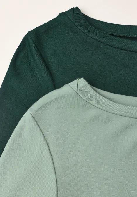 Zwei grüne T-Shirts in Dunkel- und Hellgrün, Fokus auf Ausschnitt und Schulter.