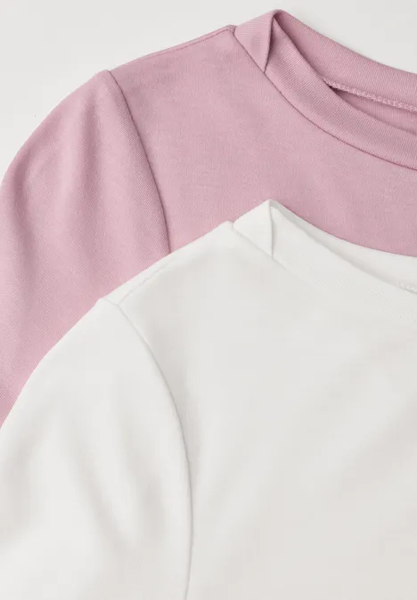 Close-up van twee over elkaar gedragen t-shirts, één wit en één roze, focus op schouders en kraag.