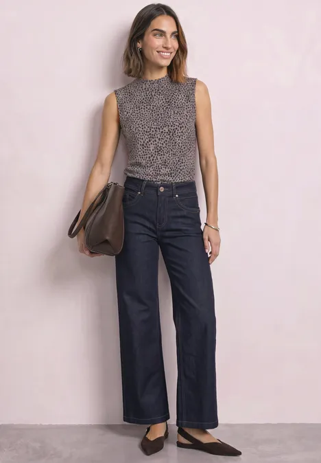 Femme en top léopard sans manches, jean large, ballerines noires et sac bandoulière marron.