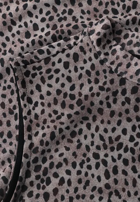 Pièce de tissu beige à motif de taches noires irrégulières avec poche latérale et surpiqûre noire.