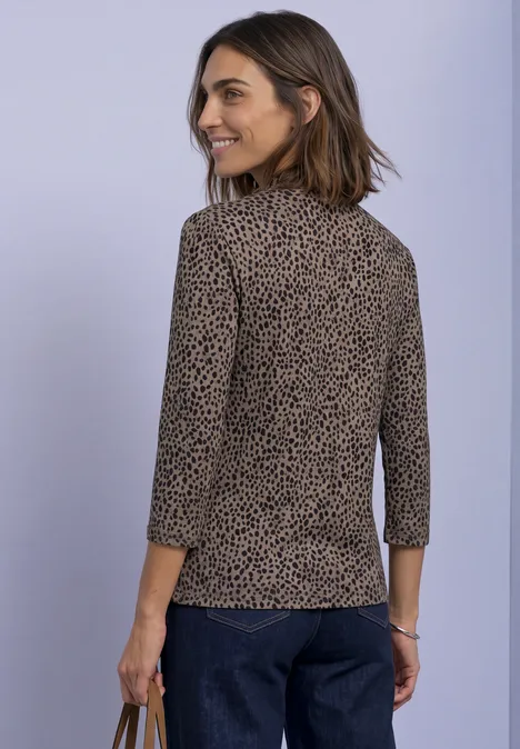 3/4-Arm Shirt mit Turtle Neck und Print Black Frau in seitlicher Ansicht trägt braunes, gepunktetes Oberteil mit 3/4-Ärmeln und dunkelblaue Hosen.