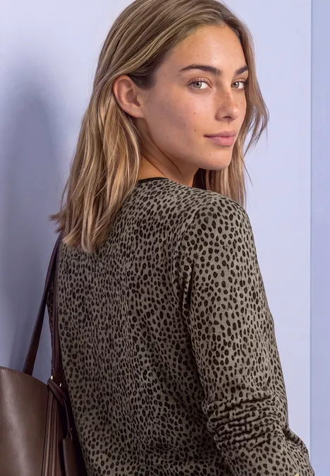 Une femme blonde en haut à manches longues à motifs léopard avec un sac, regard par-dessus l'épaule.