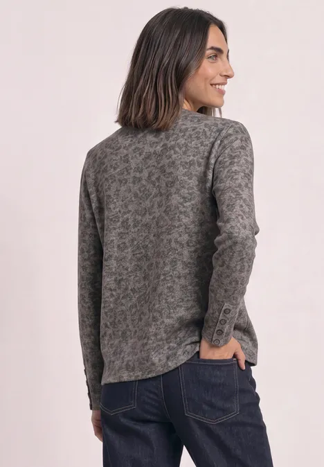 Vue de dos d’une femme portant un pull gris à motif floral et un jean foncé.
